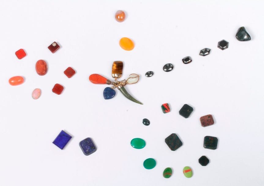 Lot de pierres sur papier : jaspe sanguin, œil de faucon, corail, pâtes de verre variées…