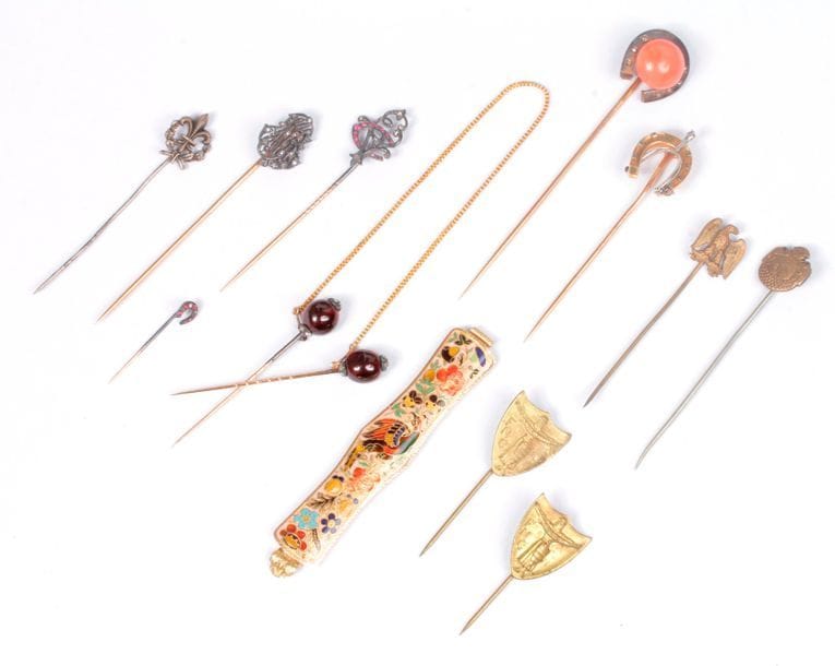 Lot de 6 épingles en or 18K (750) : les deux premières sommées de chiffres agrémentés de diamants taillés en roses ; les trois suivantes ornées de fers à cheval, l'une sertie d'une pastille de corail ; la 6e double à tête de grenat. On joint un élément en or 18K (750) à décor émaillé polychrome représentant un oiseau dans des fleurs et feuillages, poinçon pour Paris 1819-1838 ; une épingle en métal sommée d'une fleur de lys (signée Mellerio) ; et 4 épingles en métal. Poids brut : 35 g