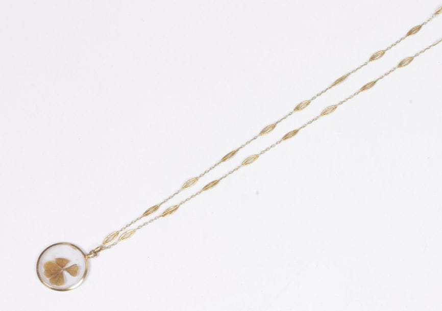 Collier en or 18K (750), articulé de maillons ovales, retenant un pendentif en or 18K orné d'un trèfle à 4 feuilles sous verre. Travail français du début du XXe siècle. Poids brut : 9,3 g