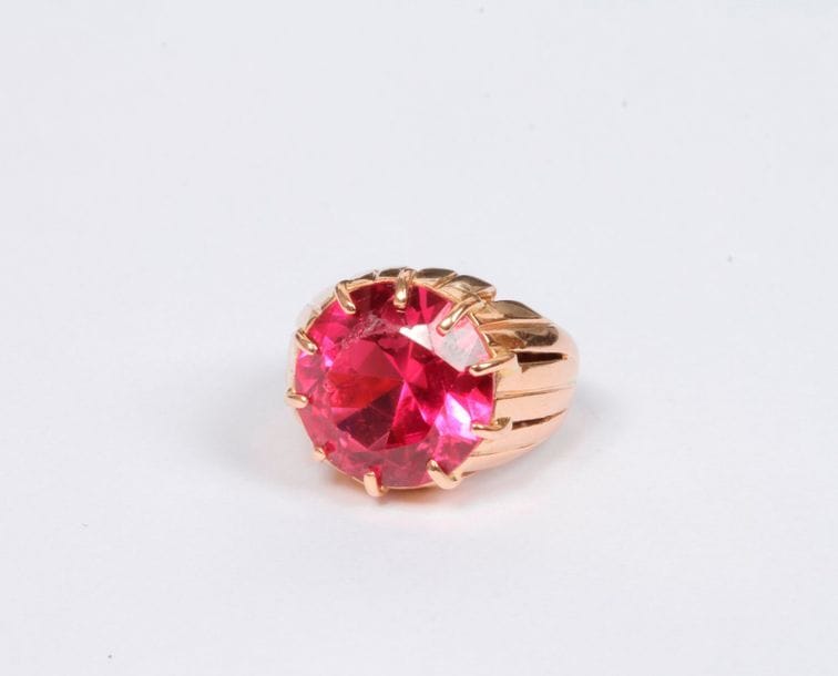 Bague en or rose 18K (750), ornée d'une pâte de verre rose ronde. Tour de doigt : 55/56. Poids brut : 10,3 g