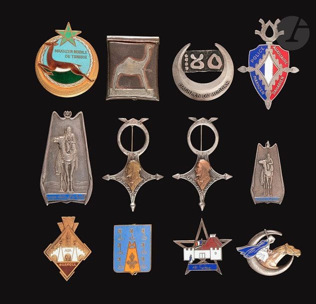 12 insignes Goums - Sahariens MSTG, DP, 2x Mahzen Saharien(1 en argent), Maghzen Méhariste d’Assa 2e modèle (artisanale) Mahzens Sahariens, 2x Mahzen El Oued (Gd et petit), Mahzen Hoggar, de Ouargla, Matmata (ajouré) MST 2e modèle Dr Ber, MMT. 