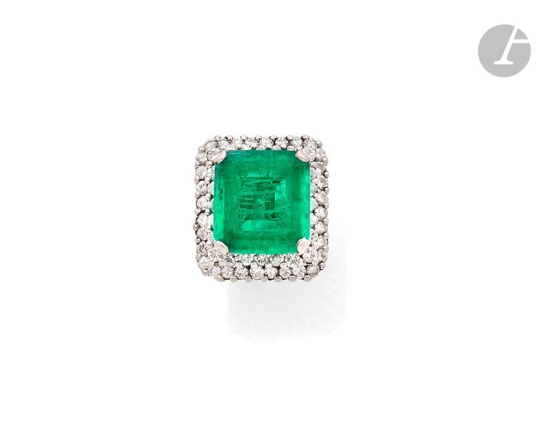 Bague en fils d’or gris 18K (750), ornée d’une émeraude rectangulaire taillée à pans dans un double entourage de diamants ronds de taille brillant. 
Dimensions de l’émeraude : 17,4 x 16 x 8,5 mm environ. 
Tour de doigt : 50. 
Poids brut : 20,6 g
 L’émeraude accompagnée d’un rapport GEM Paris (2019) attestant : origine Russie (Oural), modification par imprégnation modérée d’huile n’affectant pas sensiblement l’aspect de la pierre (E3-2).