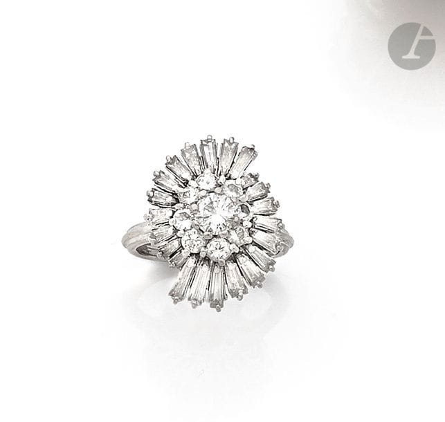 Bague tourbillon en fils d’or gris 18K (750), sertie d’un diamant rond central dans deux entourages de diamants ronds ou trapèzes. Travail des années 1970. 
Tour de doigt : 46. 
Poids brut : 5,5 g