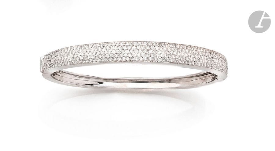 Bracelet ouvrant en or gris 18K (750), à demi pavé de diamants ronds. 
Longueur : 17 cm environ. 
Poids brut : 26,7 g
