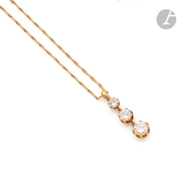 Pendentif en or jaune 18K (750), orné de 3 diamants ronds de taille brillant en chute, coulissant sur une fine chaîne en or 18K. 
Hauteur : 2,4 cm environ. 
Poids brut : 3,9 g