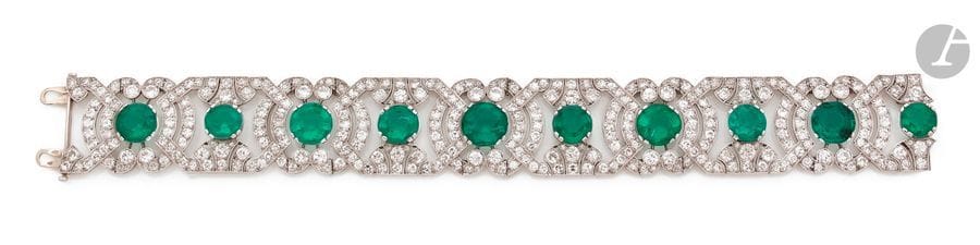 JANESICH Bracelet en platine, articulé de motifs géométriques quadrangulaires ou arrondis altérnés, imbriqués sertis de diamants ronds, chaque maillon centré d’une pierre verte synthétique. Signé et numéroté. Travail français des années 1925. 
Dimensions : 2,2 x 18,5 cm environ. 
Poids brut : 52,7 g (cliquet en or gris 18K)