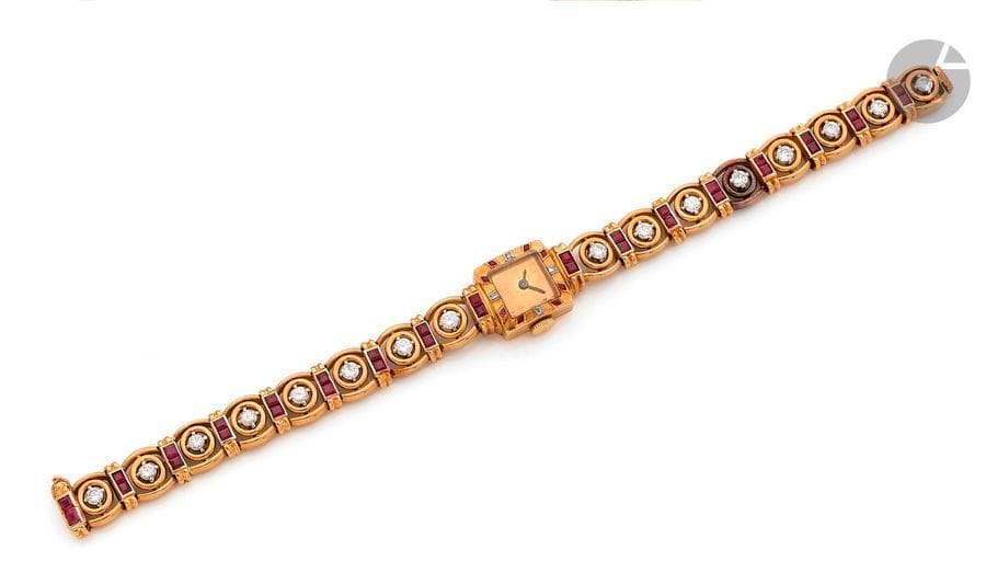 CYMA
Montre de dame en or jaune 18K (750), cadran carré, bracelet articulé en or 18K articulé de diamants ronds scandés de paires de rubis calibrés, mouvement mécanique. Mouvement et boîtier signés et numérotés. Travail des années 1950. 
Longueur : 16,5 cm environ. 
Poids brut : 35,6 g (mouvement à réviser, chocs)
