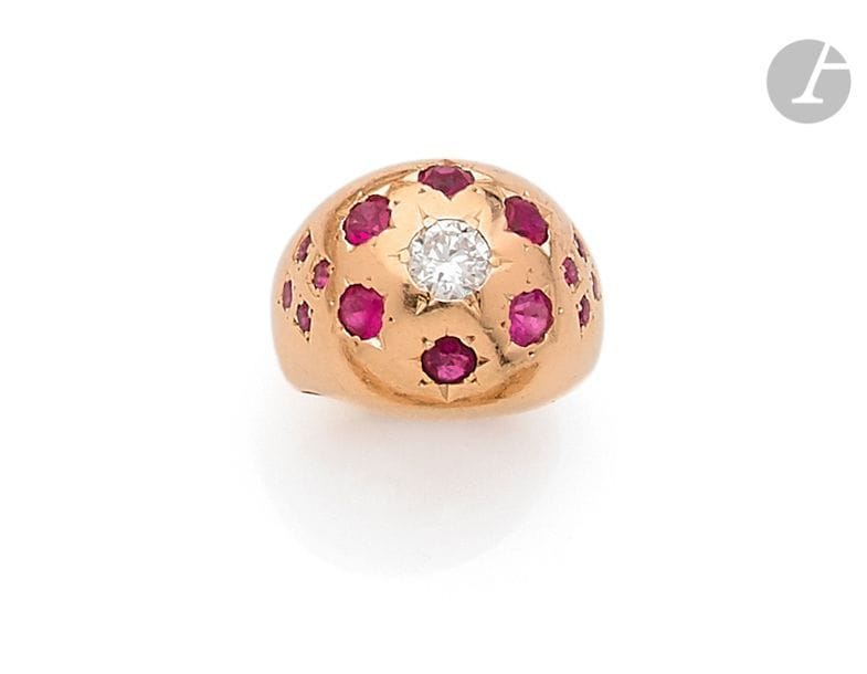 Bague de petit doigt en or rose 18K (750), ornée d’un diamant rond dans un semis de rubis ronds sertis dans des étoiles. Travail français des années 1940. 
Tour de doigt : 46. 
Poids brut : 7 g