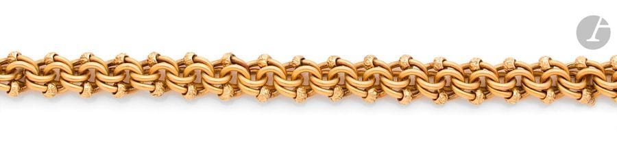 Bracelet en or 18K (750), articulé de maillons striés enroulés sur eux-mêmes ponctués de motifs ciselés de fleurs stylisées. Travail français de la fin du XIXe siècle. 
Longueur : 20,5 cm environ. 
Poids : 27,5 g