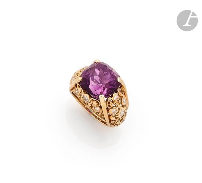 CARTIER
Bague en or jaune 18K (750), sertie d’une améthyste facettée coussin, la corbeille ajourée de feuillages stylisés piqués de diamants ronds de taille ancienne. Signée. Travail français des années 1950. 
Tour de doigt : 52/53. 
Poids brut : 11,8 g
