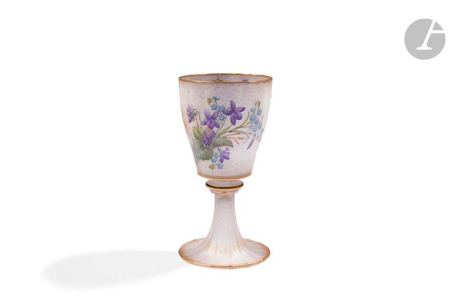 DAUM NANCY
Violettes et myosotis
Très rare vase calice ou verre à pied.
Épreuve en verre au décor tournant finement dégagé à l’acide et rehaussé aux émaux polychromes sur un fond givré.
Présente également un monogramme à l’or formant décor.
Le col, la base et la bague frottés à l’or. 
Signé DAUM Nancy France à la Croix de Lorraine, en gravure sous la base.
Hauteur : 15,5 cm 