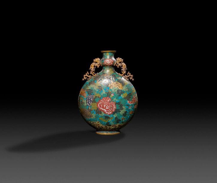 CHINE - Époque JIAQING (1796-1820)
Grande gourde en bronze et émaux cloisonnés à décor polychrome de pivoines dans leur feuillage sur fond bleu turquoise, le pied orné d’une frise de grecques, les anses en forme de qilin tenant des rinceaux feuillagés. 
H : 54 cm