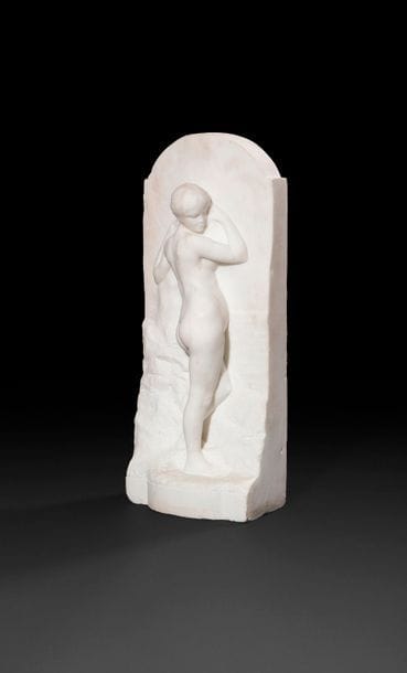 Alfred Boucher (1850-1934)
Jeune fille à la longue chevelure et aux bras repliés, dite aussi « la jeune fille au rocher »
Haut-relief en marbre blanc
Signé « A. BOUCHER »
H :47,5 cm, L : 20 cm, P : 12,5 cm

Œuvres en rapport :
- Alfred Boucher, La Philosophie de l’histoire, haut-relief en plâtre, vers 1902-1903, dim. : 168 x 43 x 51 cm, Nogent sur Marne ;
- Alfred Boucher, La Philosophie de l’histoire, dim. 67,5, x 33,5 x 12 cm, signé A Boucher en bas à gauche, marbre de carrare, musée Camille Claudel de Nogent-sur-Seine, inv. 2 000.3. 

Bibliographie :
- Alfred Boucher 1850-1934 : Sculpteur-Humaniste, Nogent-sur-Seine, 2000, p. 54, cat. n° 52
- Jacques Piette, Alfred Boucher 1850-1934, l’œuvre sculptée, catalogue raisonné, Paris, Mare et Martin, 2014, modèles de la série répertoriés sous les numéros A56 et A57, pp.238-243.
Alfred Boucher, le maître de Camille Claudel, réalise son œuvre La Philosophie de l’Histoire dans le contexte d’une commande pour des monuments à Lyon et au cimetière du père Lachaise en hommage à Auguste Burdeau, politique et professeur (1851-1894). Cette sculpture qu’il présente au Salon de 1898 sous le n° 3197 et à l’Exposition Universelle de 1900 a été suivie d’un certain nombre d’exemplaires de diverses dimensions avec des variantes dans l’attitude de la jeune femme. Ils correspondent probablement aux diverses études pour lesdits monuments : entièrement dénudée, les bras levés et le regard pensif, notre jeune fille vue de dos présente une attitude qui a clairement abandonnée sa position initiale : la jeune fille était en effet tournée vers une stèle où elle portait une inscription. A l’instar des autres versions, elle a gardé sa position debout contre la paroi d’un rocher, la tête tournée vers la droite. La forme et les dimensions du haut relief la rapprochent de la sculpture illustrée sous les numéros A57-2 et A57-3 du catalogue raisonné de l’artiste (p.243).