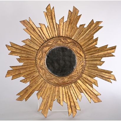 Sun-shaped mirror in gilded and carved wood....