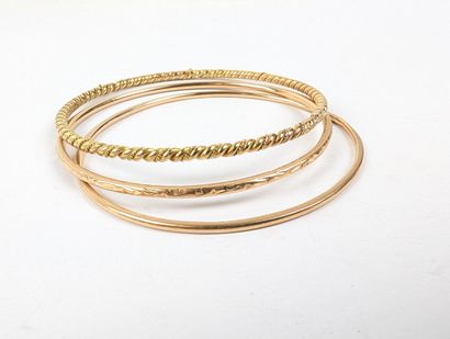 Trois bracelets joncs dépareillés en or jaune...