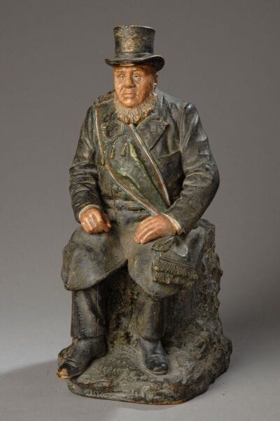 A tobacco jar depicting a figure seated on...