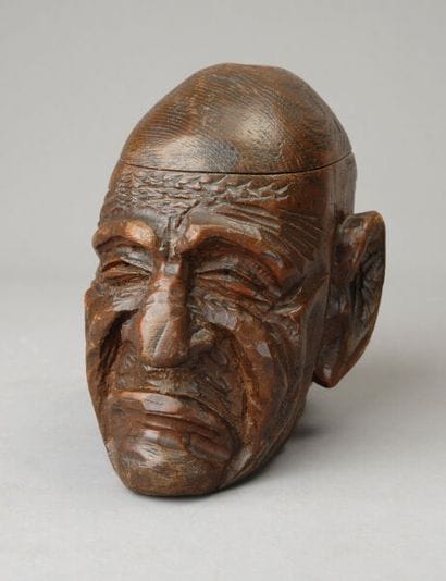 A tobacco jar, carved from exotic wood, depicting...