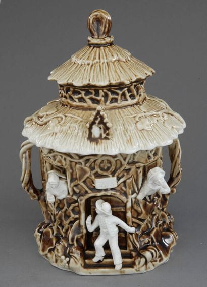 A large beige and cream tobacco jar depicting...