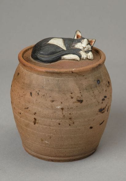 A tobacco jar shaped like an urn, unglazed...