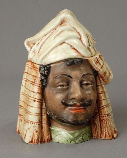 A tobacco jar depicting the head of a smiling...