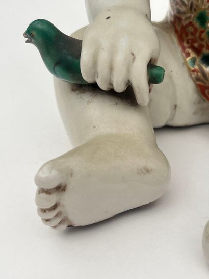 Enfant assis en porcelaine, tenant un oiseau...