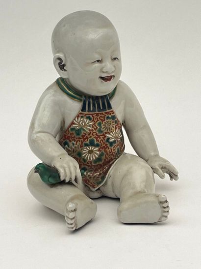 Enfant assis en porcelaine, tenant un oiseau...