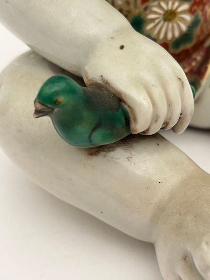 Enfant assis en porcelaine, tenant un oiseau...