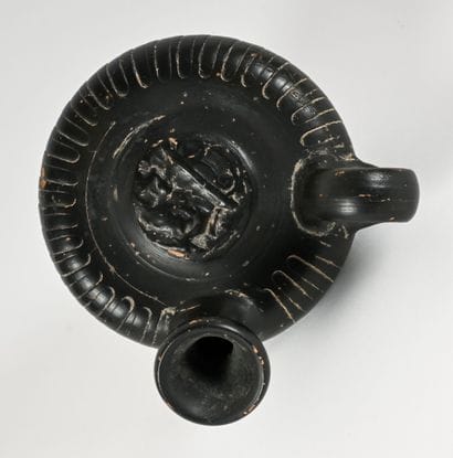 Black-glazed guttus with a tondo decorated...