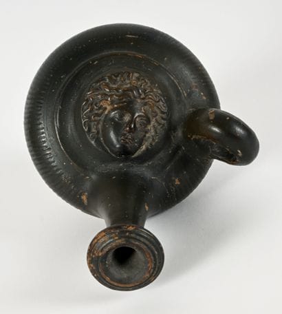 Black-glazed guttus with a Gorgon mask in...