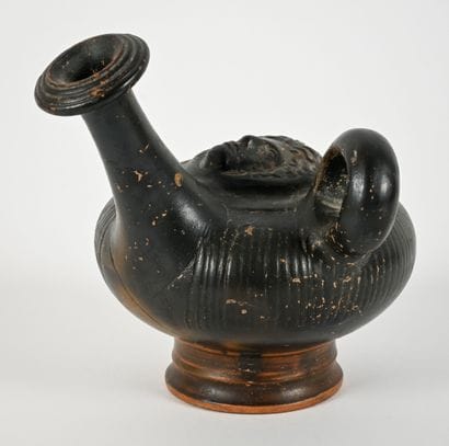 Black-glazed guttus with a Gorgon mask in...