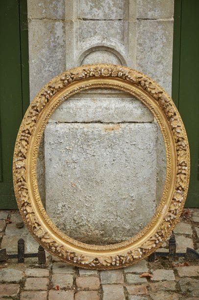 Oval carved and gilded wooden frame decorated...