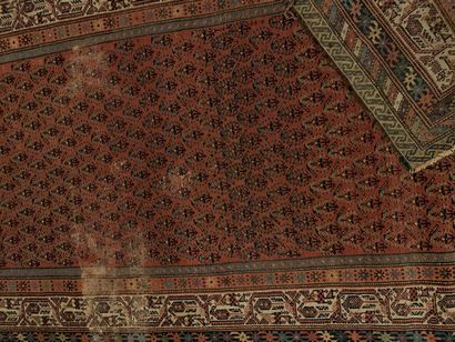 Long tapis d’orient à fond rouge à décor...