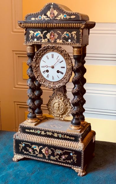 A blackened wood clock with torso columns...