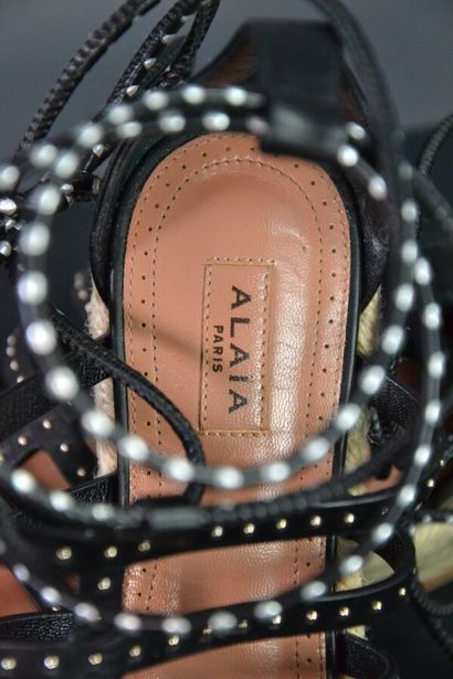 ALAIA Sandales compensées en cuir noir clouté....