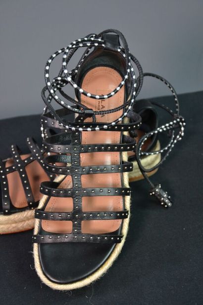 ALAIA Sandales compensées en cuir noir clouté....