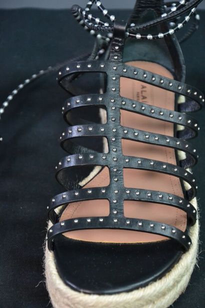 ALAIA Sandales compensées en cuir noir clouté....