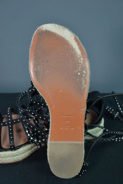 ALAIA Sandales compensées en cuir noir clouté....