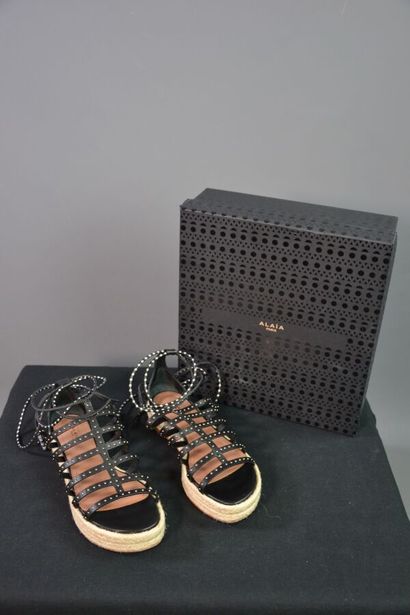 ALAIA Sandales compensées en cuir noir clouté....