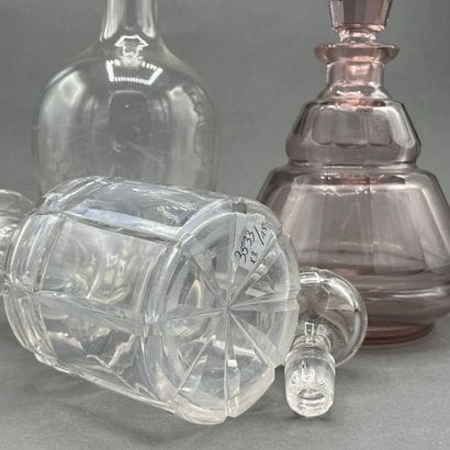 Two cut-crystal carafes, one purple-tinted...