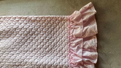 Quilted pink bedspread with frilly braid...
