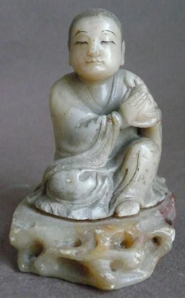 Enfant assis en stéatite. Chine, XXe siècle....