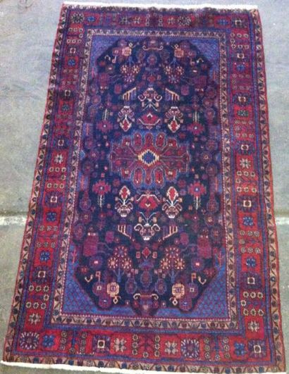 Tapis persan à fond bleu et décor stylisé....
