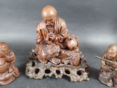 Trois sujets en bois sculpté, représentant...