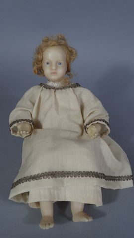 Poupon en cire assis vêtu d'une robe en tissu...