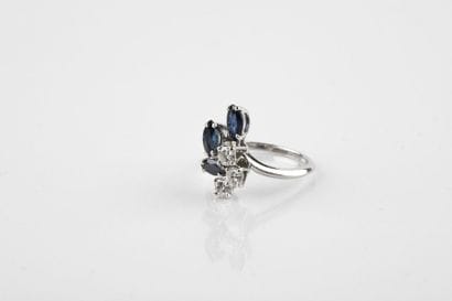 White gold ring adorned with three shuttle-cut...