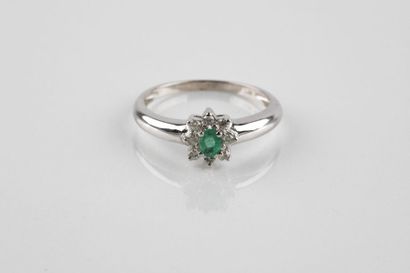 White gold ring holding an oval cut emerald...