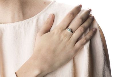 White gold ring holding an oval cut emerald...