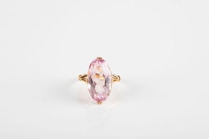 Yellow gold ring holding a shuttle-cut pink...