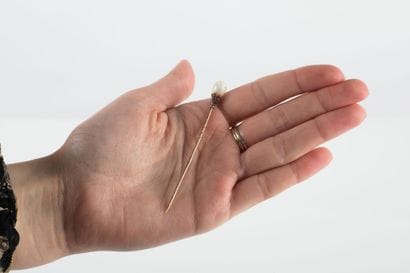 Gold pin punctuated with an opal drop in...