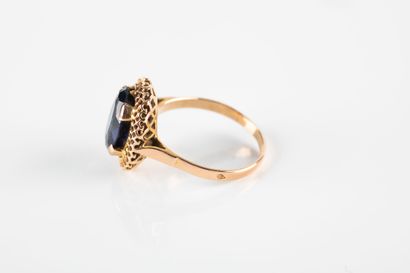 Yellow gold ring holding an oval synthetic...